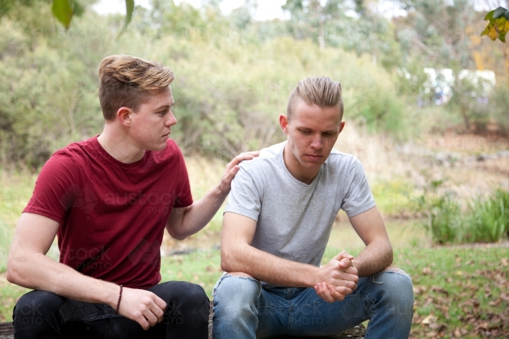 Young male same sex couple having a serious conversation in a rural setting - Australian Stock Image