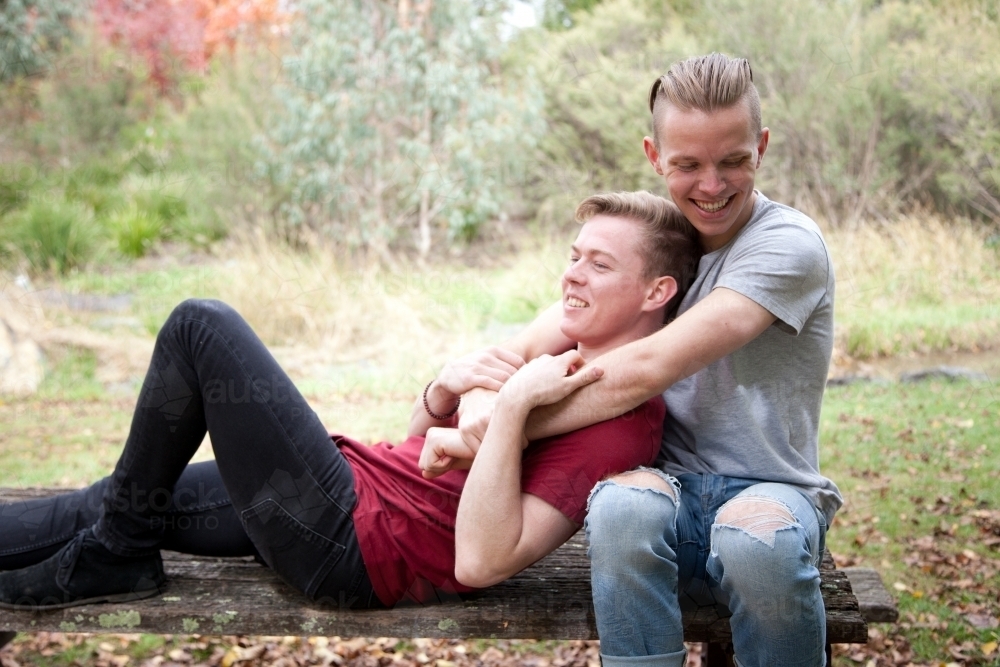 Young male same sex couple hugging in a rural setting - Australian Stock Image