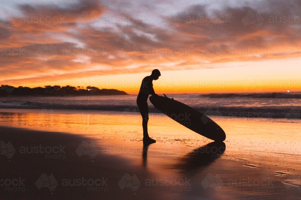 Young male surfer at sunrise - Australian Stock Image