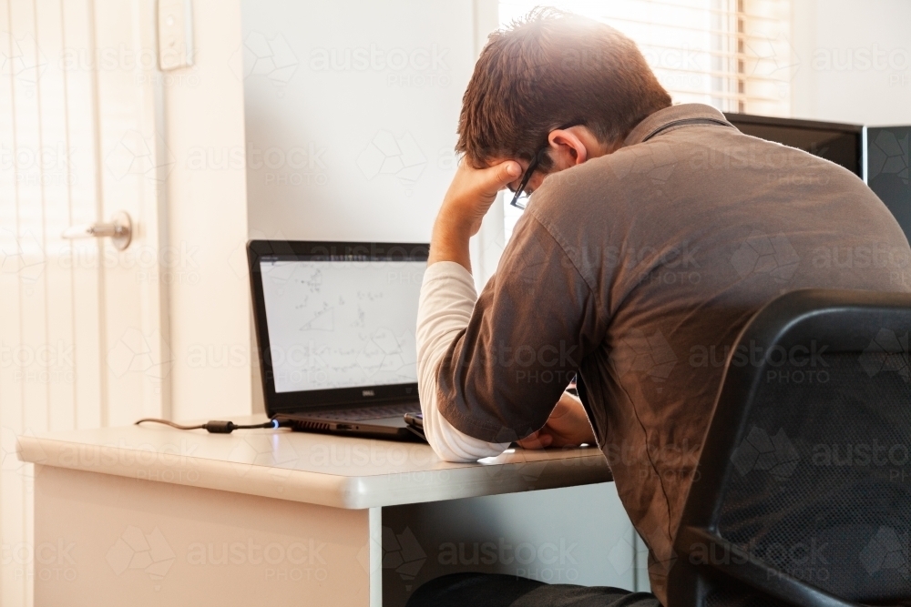 Young male uni student studying math on laptop for exams from home during covid-19 - Australian Stock Image