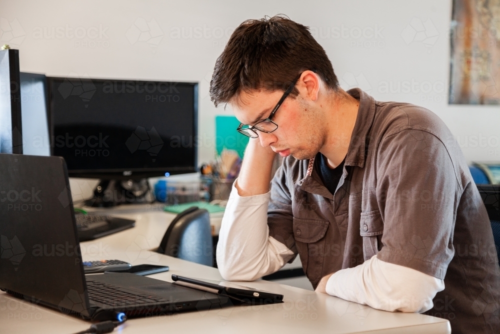 Young male uni student studying math on laptop for exams from home during covid-19 - Australian Stock Image