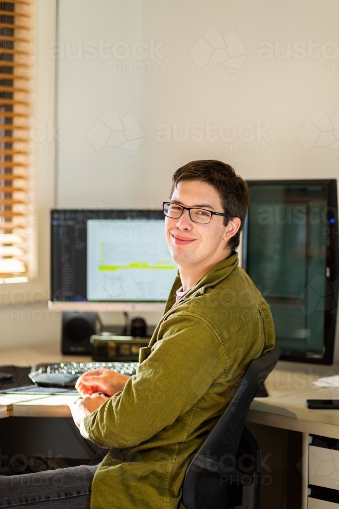 Image of Young male uni student studying on computer at desk - Austockphoto