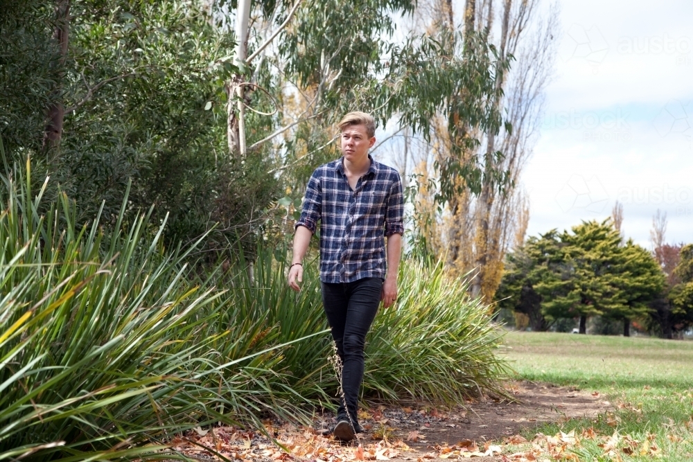 Young male walking alone in a park - Australian Stock Image