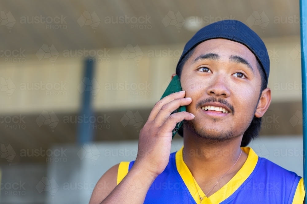 Young male with cap on backwards talking on mobile phone - Australian Stock Image
