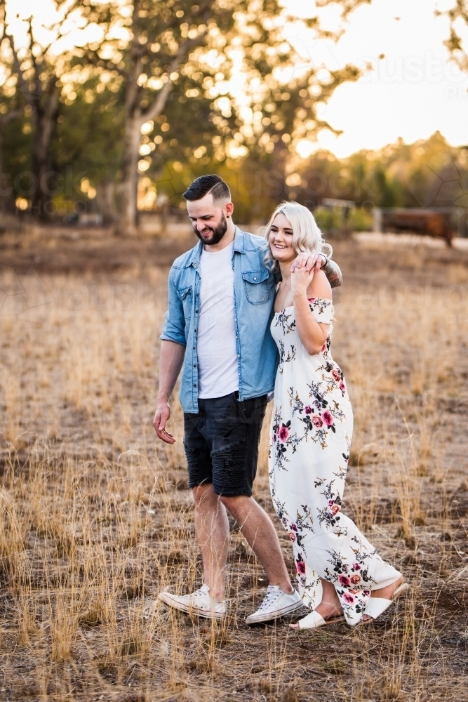 Young man and woman walking with arms around each other - Australian Stock Image