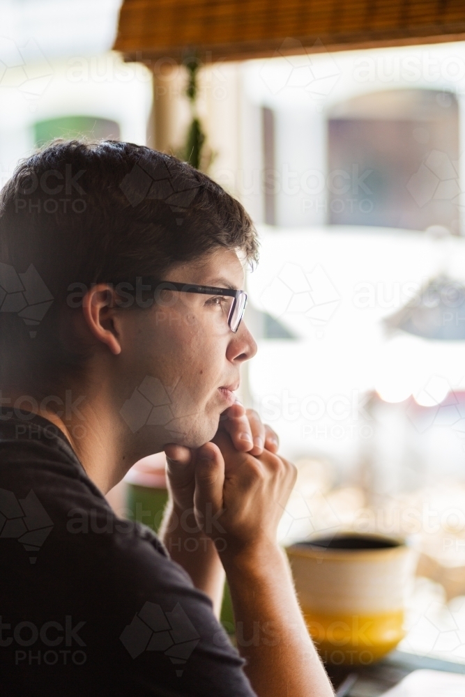 Young man at a cafe looking out the window - Australian Stock Image