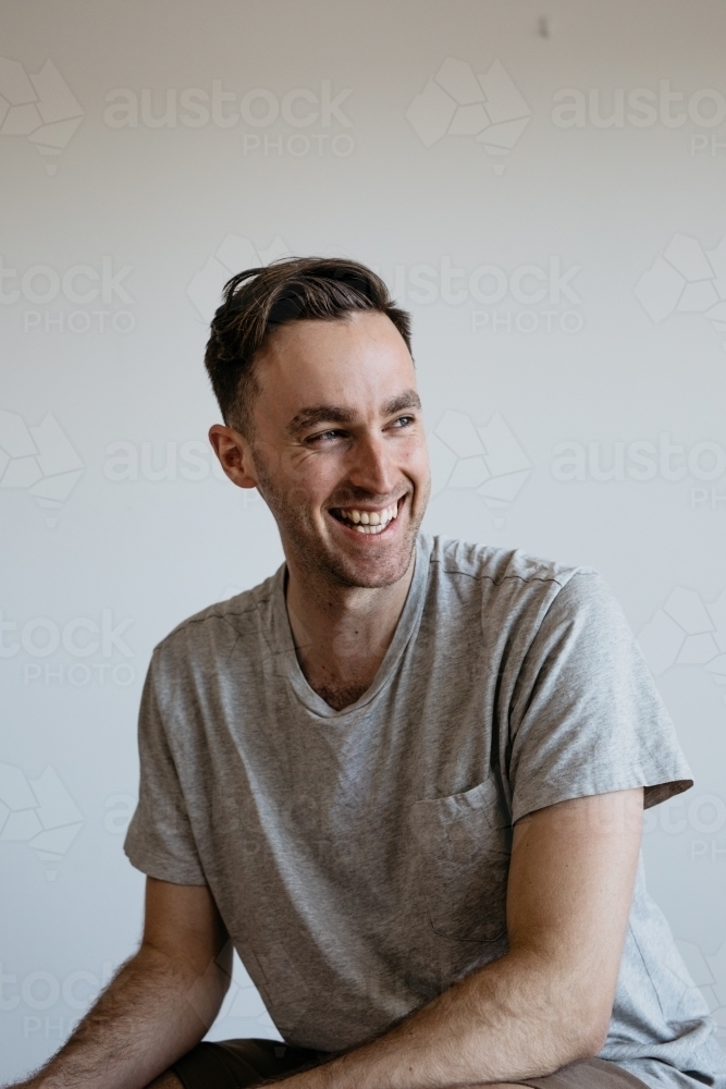 Young man big laughter grey shirt plain background - Australian Stock Image