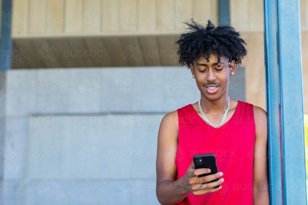 Young man casually looking at his smartphone - Australian Stock Image