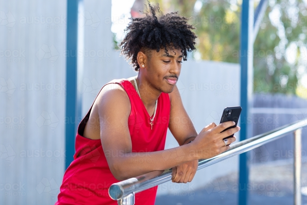 Young man casually looking at his smartphone - Australian Stock Image