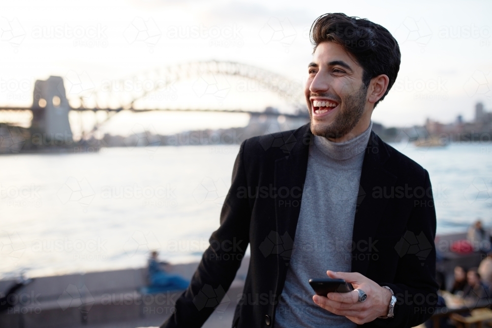Young man enjoying time in front of Sydney Harbour Bridge - Australian Stock Image