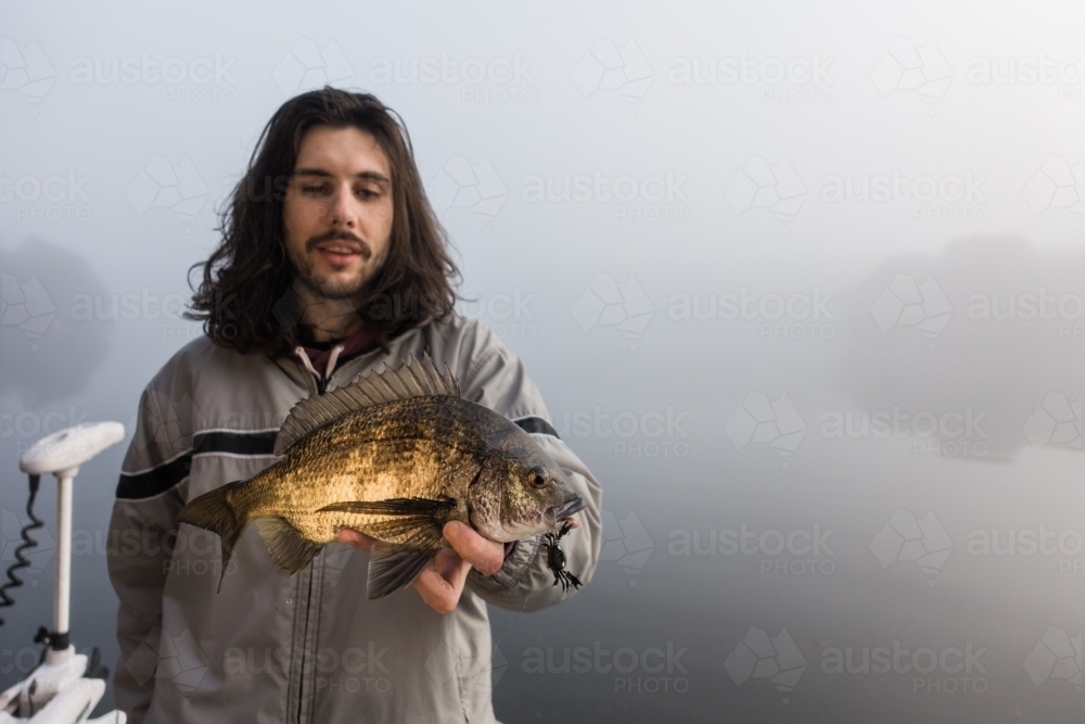 Young Man holding a Bream he Just Caught - Australian Stock Image