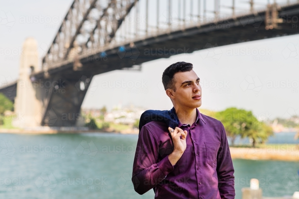 young man in suit standing under Sydney Harbour Bridge - Australian Stock Image