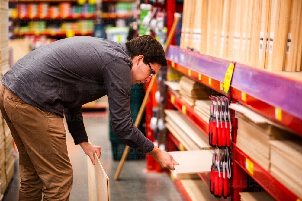 Young man in wood section of hardware store - Australian Stock Image