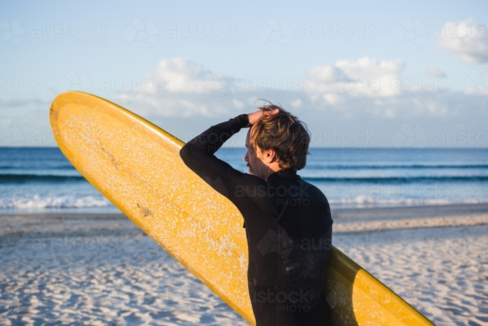 Young man looking out to the surf during sunset - Australian Stock Image