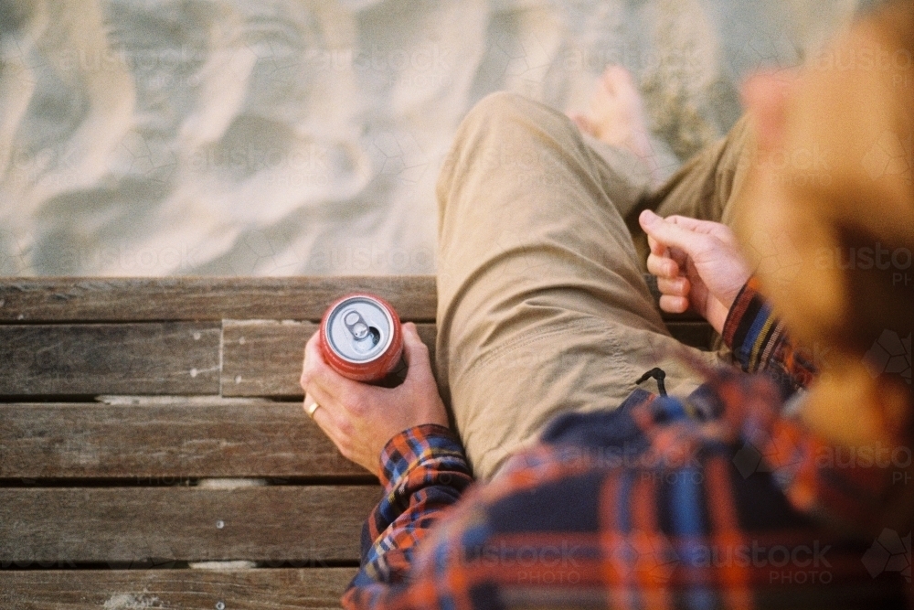 Young man on the beach drinking a beer - Australian Stock Image