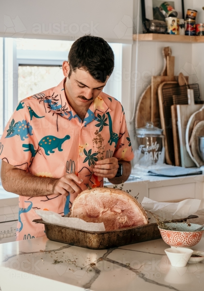 Young man prepares Christmas ham. - Australian Stock Image
