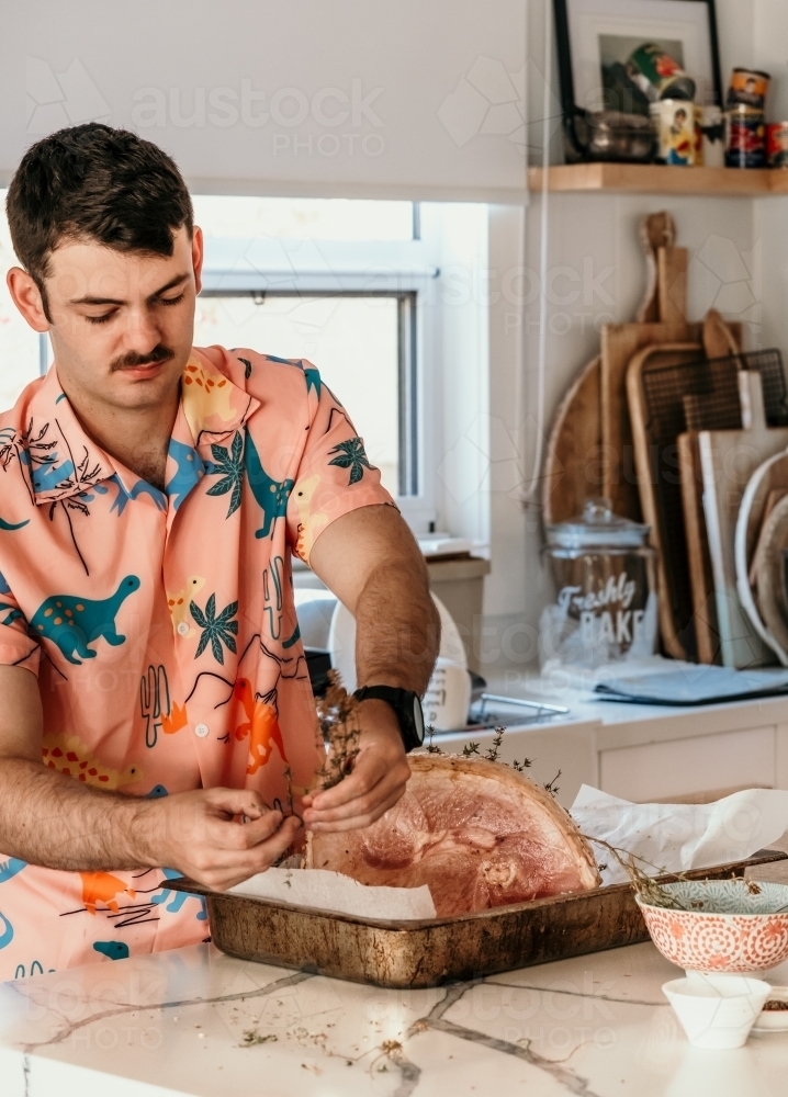 Young man preparing Christmas ham. - Australian Stock Image