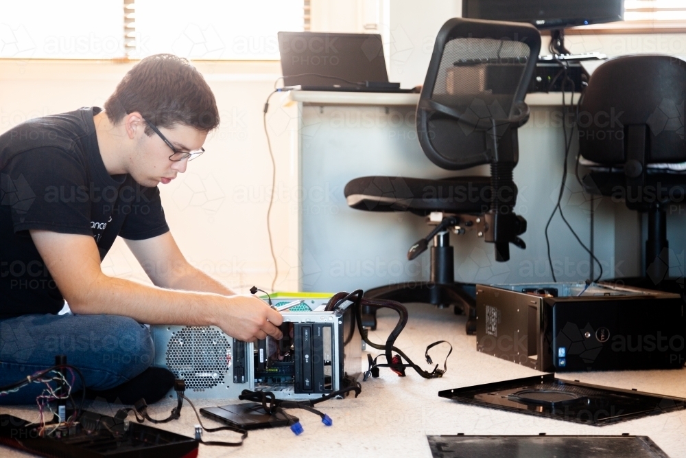 Young man pulling apart and re-building home computer - Australian Stock Image