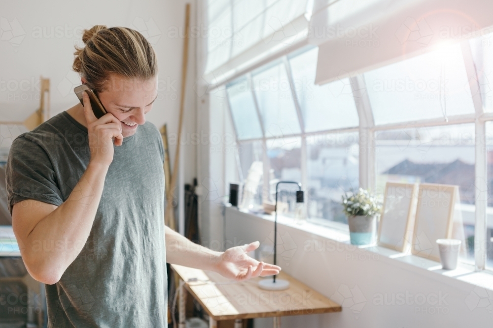 Young man questioning someone on the phone in an office - Australian Stock Image