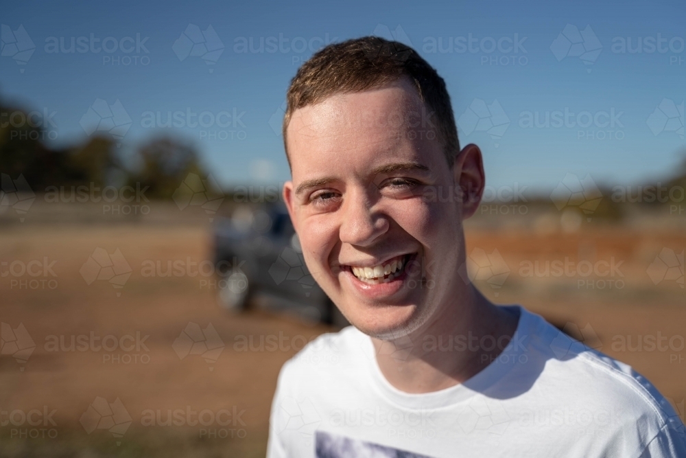 Young man smiling at camera in countryside - Australian Stock Image