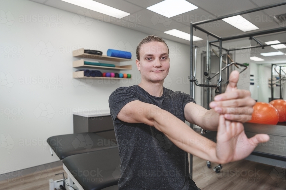 Young man stretching at physiotherapy clinic - Australian Stock Image