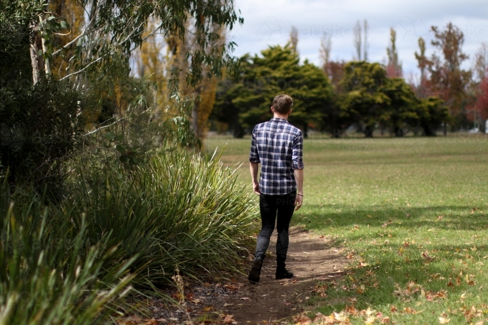 Young man walking alone along a path in nature - Australian Stock Image