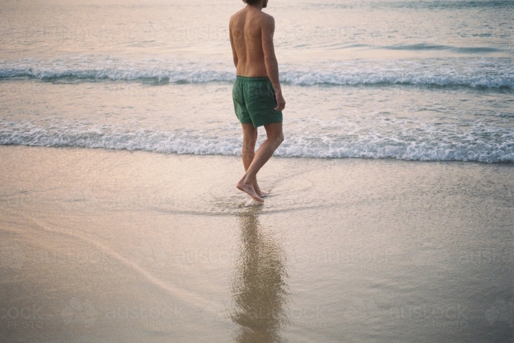 Young man walking towards the ocean - Australian Stock Image