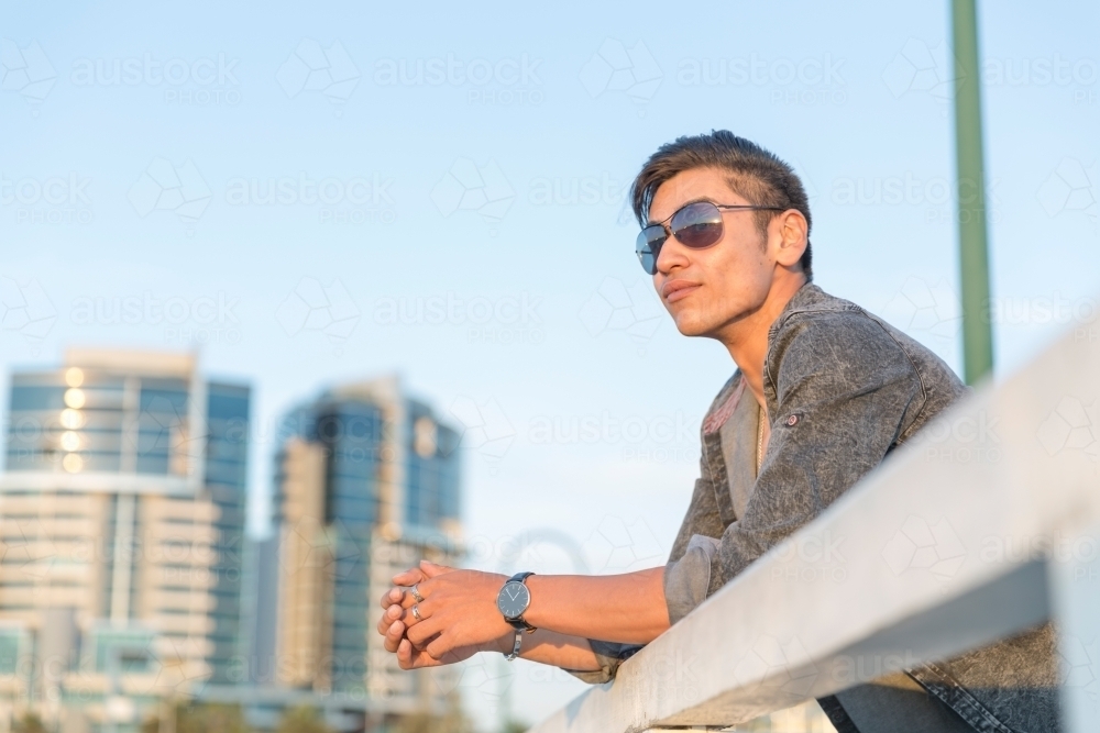 Young man watching the sunset with condos in the background - Australian Stock Image