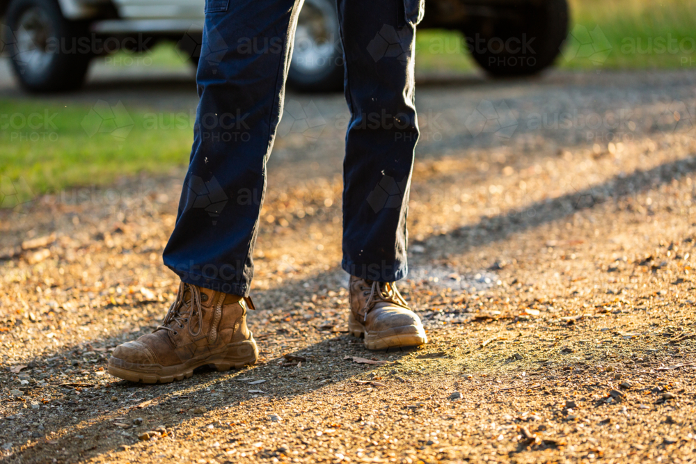 Young man wearing sturdy workwear boots standing on gravel driveway - Australian Stock Image
