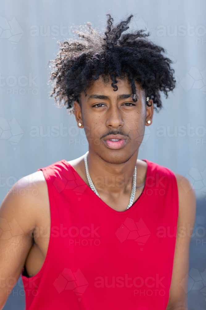 Young man with curly hair wearing red singlet - Australian Stock Image