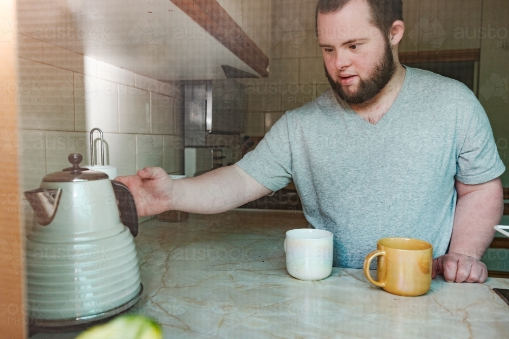 Young Man with Down Syndrome Making Two Cuppas - Australian Stock Image