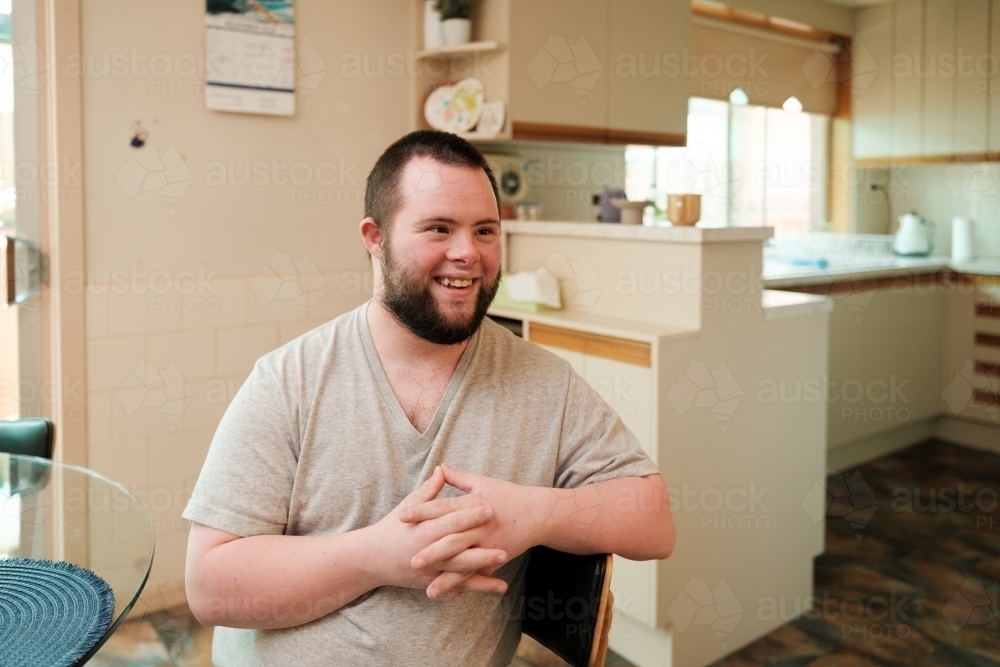 Young Man with Down Syndrome Seated in Kitchen - Australian Stock Image