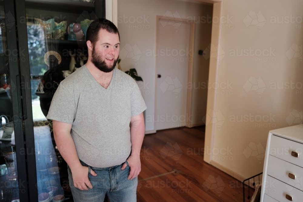Young Man with Down Syndrome Standing in Living Room - Australian Stock Image