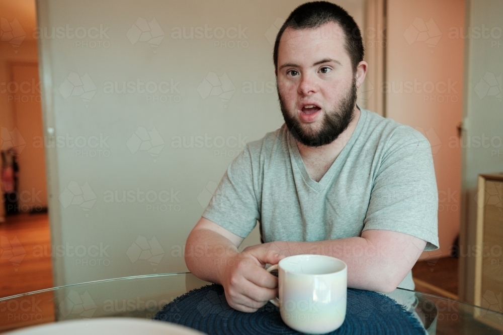 Young Man with Down Syndrome with White Cup - Australian Stock Image