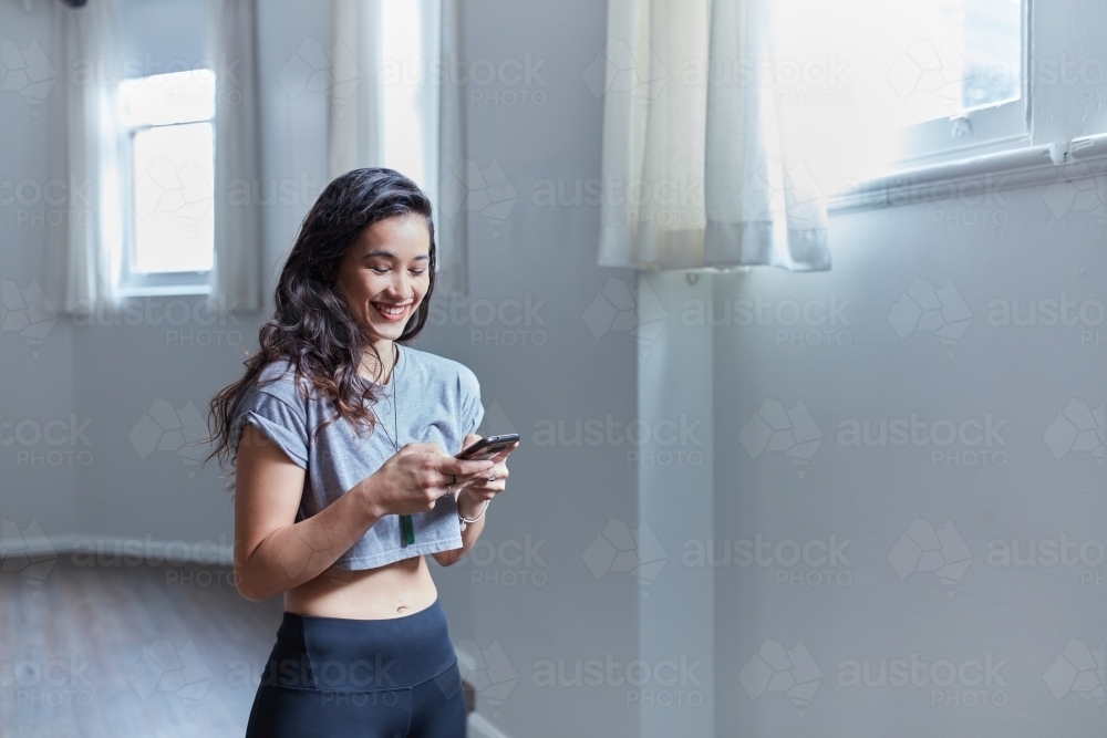 Young Maori dancer standing in studio using mobile phone - Australian Stock Image
