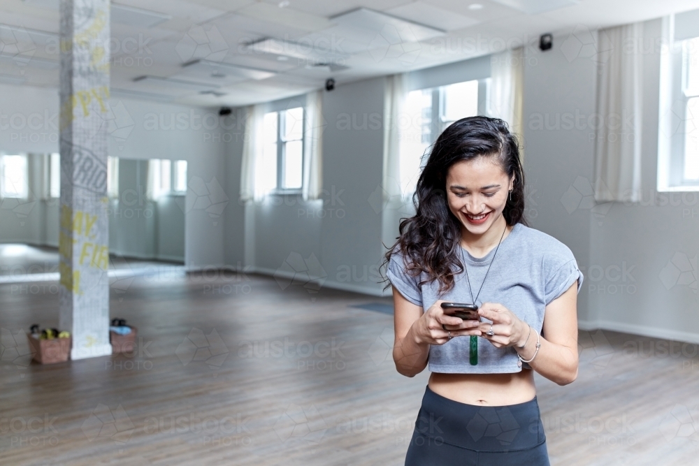 Young Maori dancer standing in studio using mobile phone - Australian Stock Image