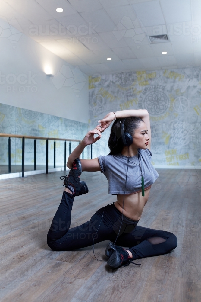Young Maori girl doing difficult yoga stretch in dance studio - Australian Stock Image