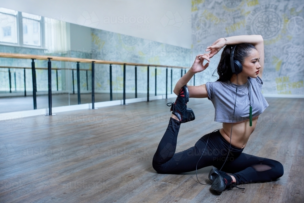 Young Maori girl doing yoga stretch in dance studio - Australian Stock Image