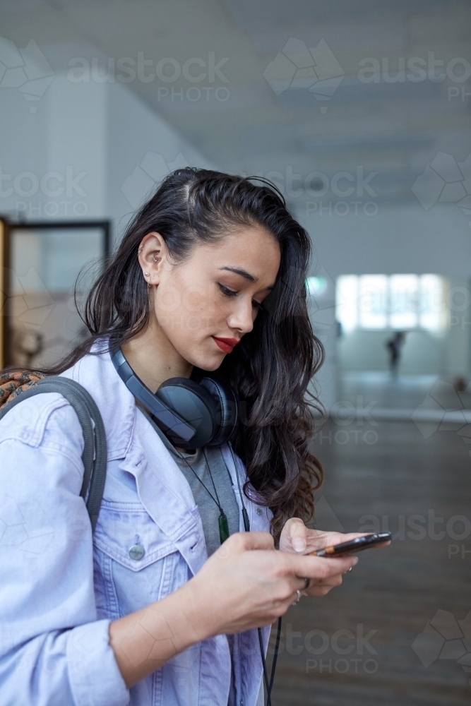 Young Maori woman checking messages in dance studio - Australian Stock Image