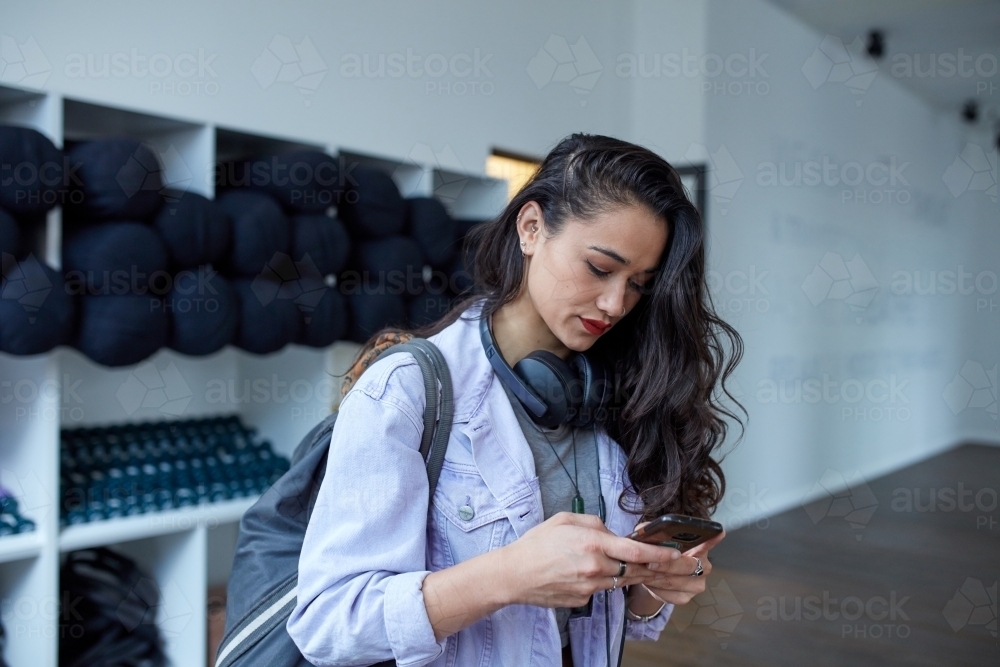 Young Maori woman checking phone at dance studio - Australian Stock Image