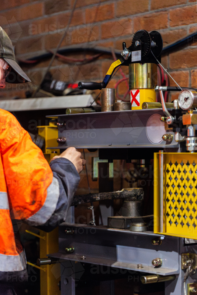 young mechanic tradie using workshop mate press tool workstation to repair car components - Australian Stock Image