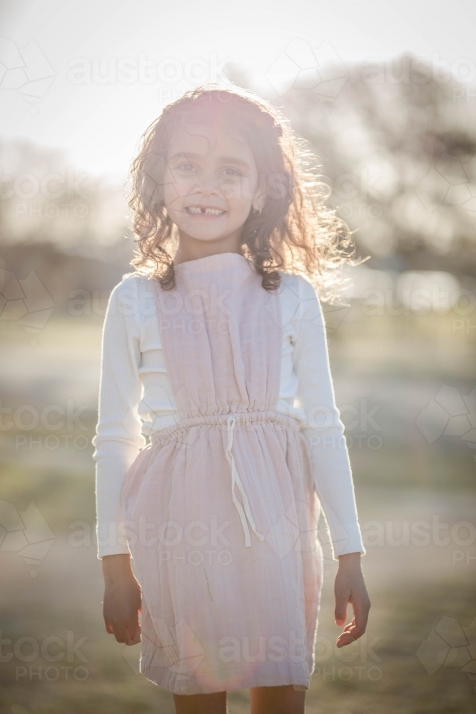 Young mixed race aboriginal and caucasian girl smiling in afternoon light - Australian Stock Image