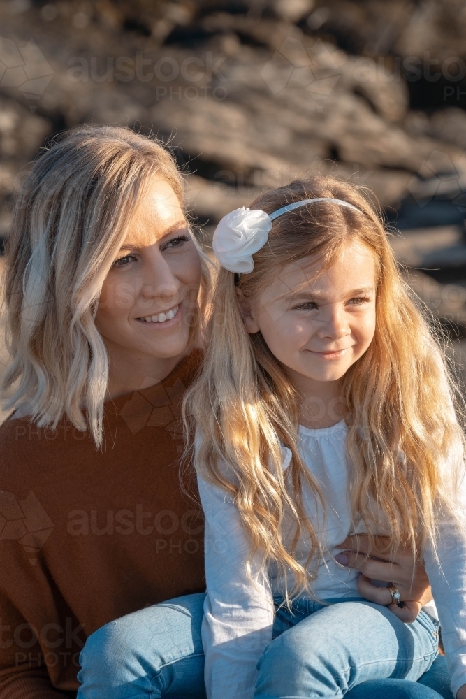 Young mother and daughter looking off camera at sunrise - Australian Stock Image