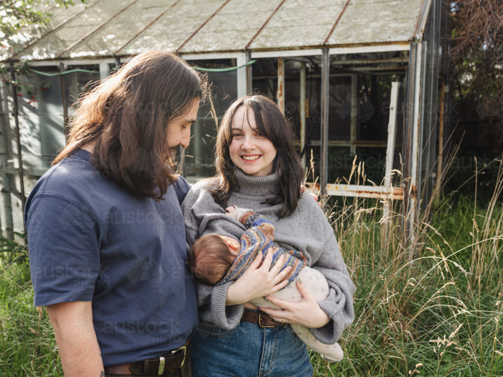 Young mother breastfeeding baby in an overgrown garden - Australian Stock Image