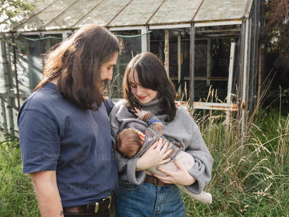 Young mother breastfeeding baby in an overgrown garden - Australian Stock Image