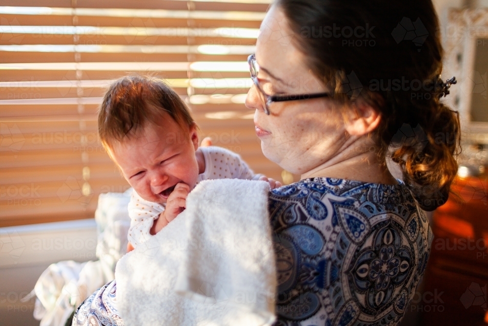Young mother comforting sad crying baby child - Australian Stock Image