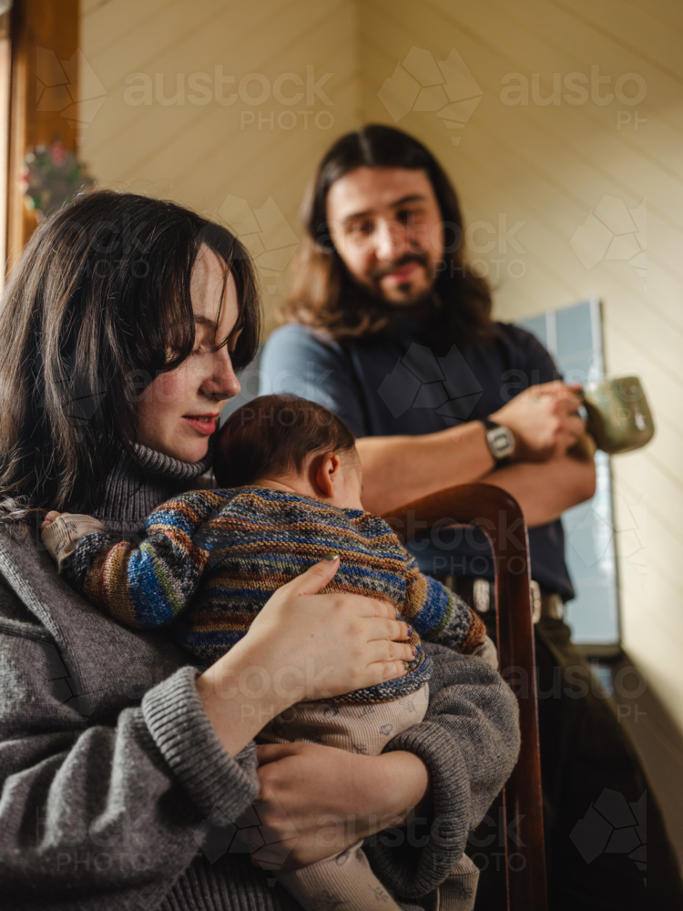Young mother holding baby dressed in striped sweater - Australian Stock Image