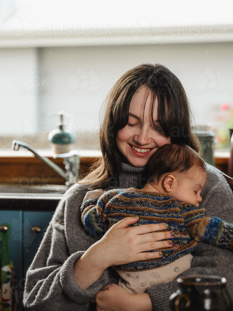 Young mother holding baby dressed in striped sweater - Australian Stock Image