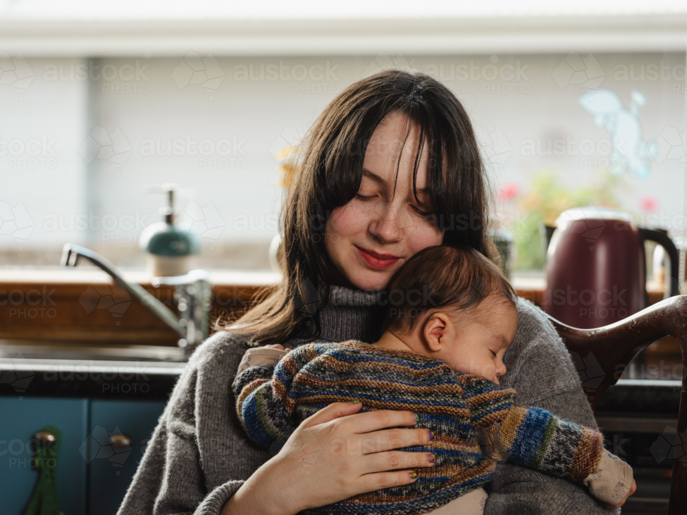 Young mother holding baby dressed in striped sweater - Australian Stock Image