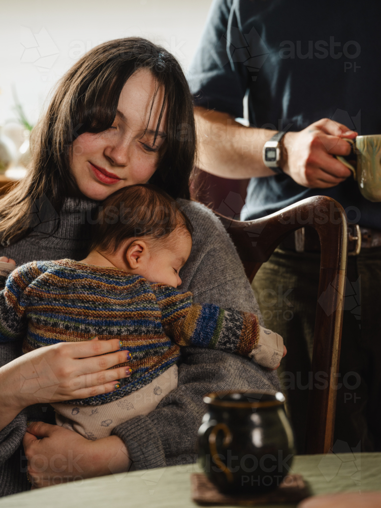 Young mother holding baby dressed in striped sweater - Australian Stock Image